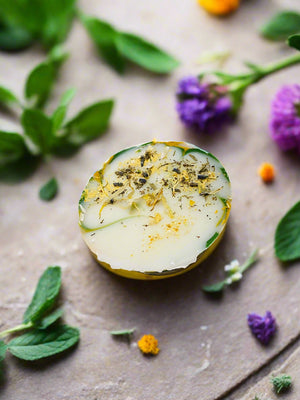 bar of round soap with herbs and flowers on table